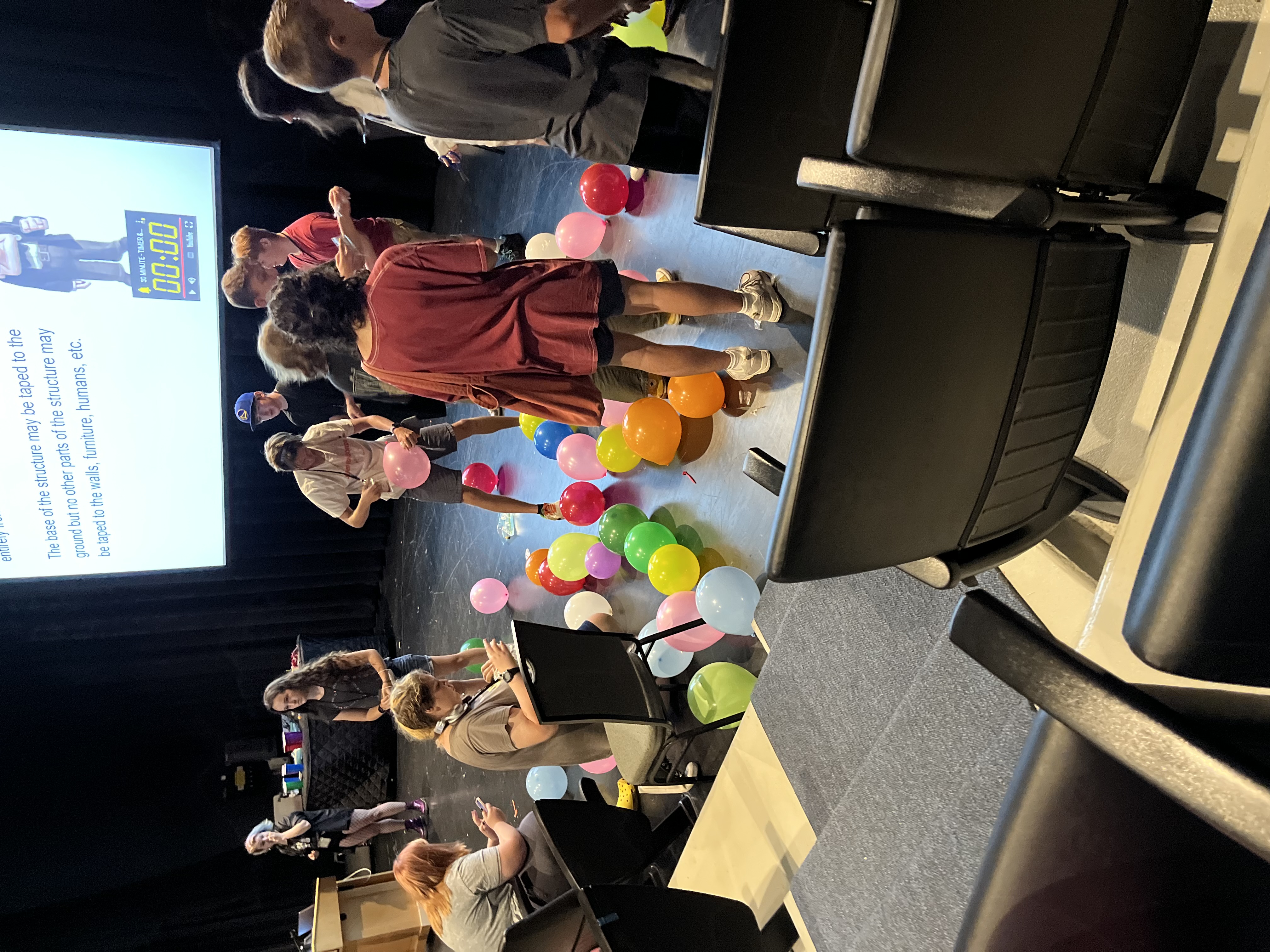 A bunch of kids working on their balloon towers, using only tape and balloons.